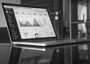 A laptop on a desk displays digital marketing dashboards with graphs, charts, and statistics on the screen.