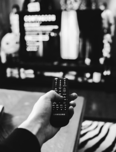 A person holds a Samsung remote control, pointed at a TV screen displaying a menu or information about search engine optimization, with the scene captured in black and white.