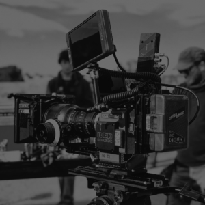 A professional RED digital cinema camera setup is positioned outdoors, with blurred crew members in the background—perfect for filming dynamic content about topics like SEO or email marketing strategies.