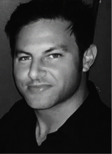 Black and white portrait of a man with short dark hair, light eyes, and a slight smile, wearing a dark collared shirt—ideal for a professional SEO or CRM profile facing the camera.