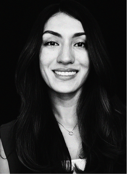 Black and white portrait of a woman with long dark hair, smiling, wearing a necklace and dark top against a black background—perfect for showcasing professionals in marketing or search engine optimization.