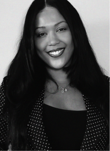 Black and white portrait of a woman with long dark hair, wearing a polka-dotted blazer, smiling at the camera—an image that captures the confident spirit of digital marketing professionals.