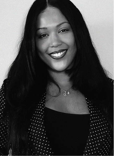 Black and white portrait of a woman with long dark hair, wearing a polka-dotted blazer, smiling at the camera—an image that captures the confident spirit of digital marketing professionals.