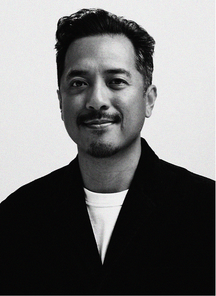 A man with short, dark hair and facial hair, wearing a dark jacket over a light shirt, smiles slightly while facing the camera against a plain background—exuding confidence often seen in digital marketing professionals.