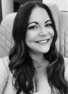 A woman with long dark hair smiles at the camera while seated in a chair with a quilted pattern. The black and white photo exudes a professional vibe, perfect for digital marketing or CRM profile images.