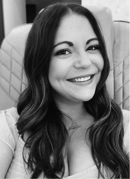 A woman with long dark hair smiles at the camera while seated in a chair with a quilted pattern. The black and white photo exudes a professional vibe, perfect for digital marketing or CRM profile images.