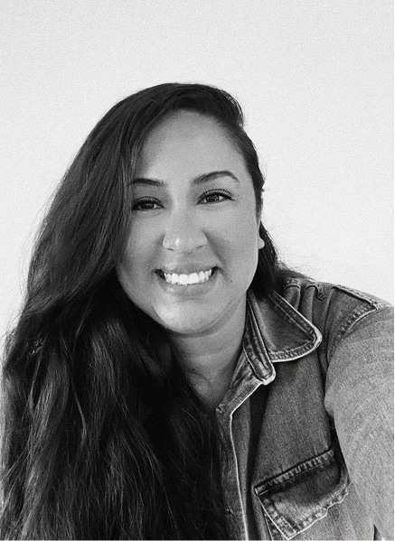 A woman with long dark hair, wearing a denim jacket, smiles at the camera against a plain light background—perfect for marketing or SEO profile photos.