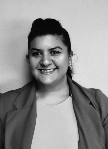 A woman with dark hair tied back, wearing a light top and a blazer, smiles at the camera against a plain background—an ideal portrait for a digital marketing or search engine optimization professional.