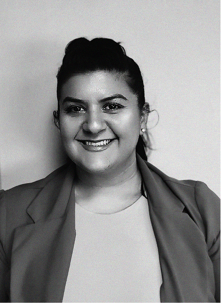 A woman with dark hair tied back, wearing a light top and a blazer, smiles at the camera against a plain background—an ideal portrait for a digital marketing or search engine optimization professional.