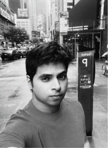 A person takes a selfie on a city street with tall buildings, cars, and a parking meter visible in the background. The black and white image evokes the organized structure often seen in crm systems.
