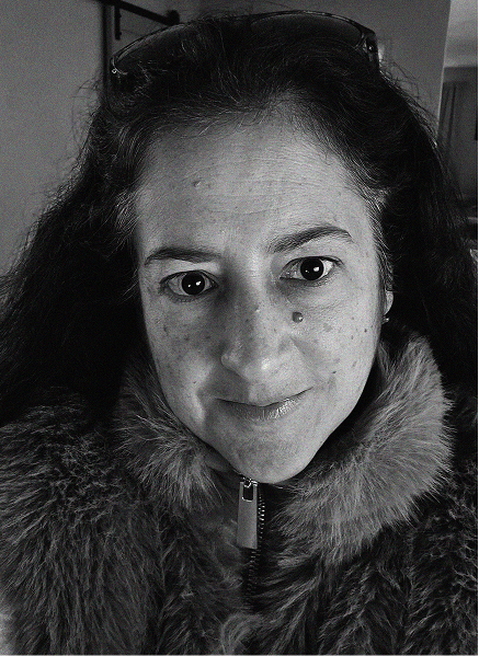 Black and white close-up of a person with long dark hair, wearing a fur-collared jacket and looking directly at the camera, evoking the bold focus needed for standout marketing or impactful email marketing campaigns.
