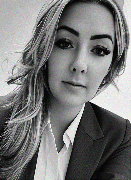 Black and white portrait of a woman with long, wavy hair in a suit jacket and white blouse, looking at the camera with a neutral expression—a professional ready to take on digital marketing challenges.