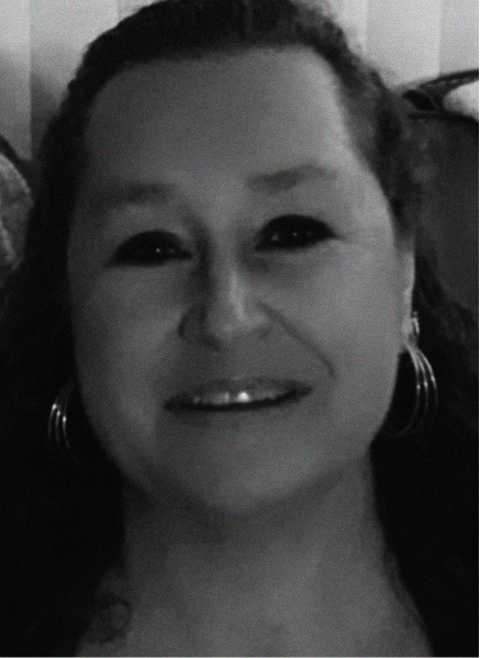 Black and white photo of a person with long curly hair, smiling, wearing hoop earrings and a dark top, seen from the shoulders up—a portrait that captures the creative spirit behind digital marketing.